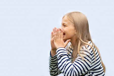Girl put her hands to her mouth and screams. Isolate on a gray background