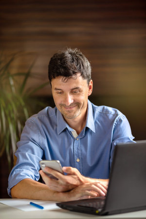 Business man works from home. He sends a message on the phone and works at the computer. Online work