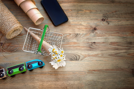 Bouquet of chamomile flowers in a shopping basket and materials for creating a bouquet on a wooden...