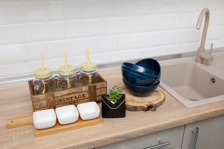 Dishes and utensils: plates, saucers on a wooden stand, lemonade jars against the background of a...