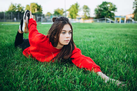 Athletic young girl do exercises in stadium. A girl in a tracksuit does sports in stadium She looking straight and smiling. Girl are having fun. She like to do excercises.の写真素材