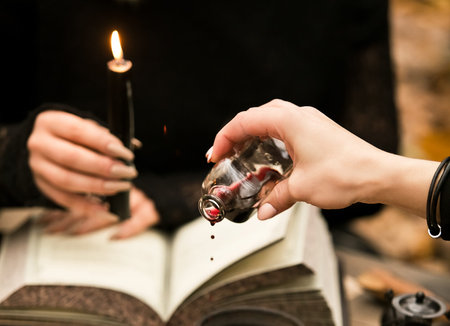 The witch conducts a ritual, drips wine on the witchcraft book
