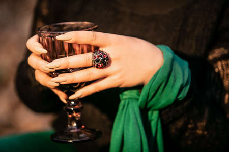 A womans hand with a ring on her finger holds a ritual glass.の写真素材