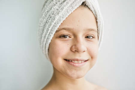 A young girl with a towel on her head and problem skin. Skin care concept for teenagersの写真素材