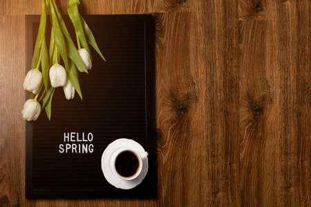 Cup of coffee and white tulips on a felt board with the inscription in English spring. Flat lay, top view, copy space.の写真素材