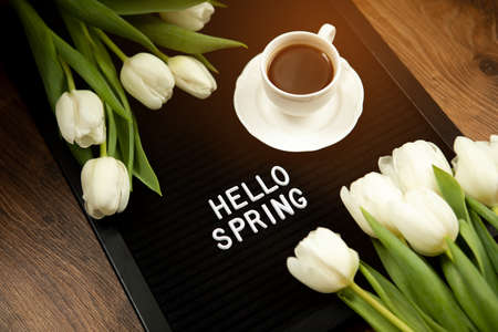 Cup of coffee and white tulips on a felt board with the inscription in English spring. Flat lay, top view, copy space.の写真素材