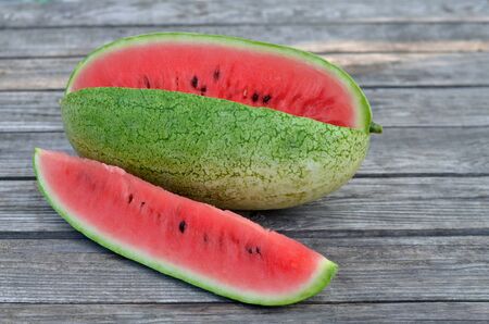 Long ripe sweet watermelon on an old wooden table. Close-up, selective focus.の写真素材