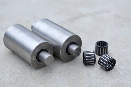 The manufacture of metal products, needle bearings and shafts on a grey concrete background, close-up. Industrial conceptの写真素材