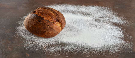 Bread with a crisp crust on the kitchen table sprinkled with flourの写真素材