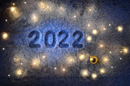Inscription about the new year 2022 on the snow in winter with christmas lights.の写真素材