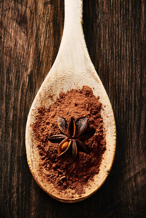 Star anise on cocoa and wooden spoon on wooden tableの写真素材