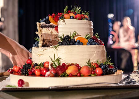 the newlyweds together cut a piece of a beautiful, appetizing, wedding cakeの写真素材