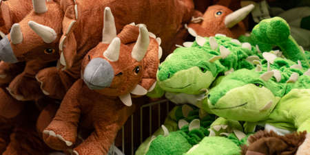 Lots of stuffed toys in the form of brown and green dinosaurs.の写真素材