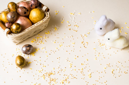 Easter holiday. Beautiful, mother-of-pearl eggs in a small basket. Two small rabbits next to the...