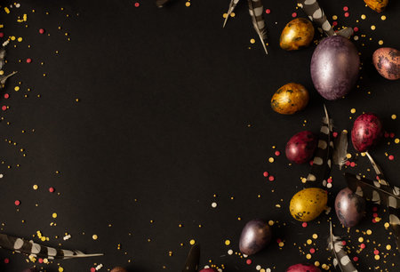 Easter holiday. Multi-colored, mother-of-pearl chicken and quail eggs lie on a black background,...