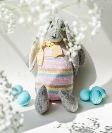 Easter. A festive Easter bunny, a toy, stands next to a basket containing decorated, festive Easter...