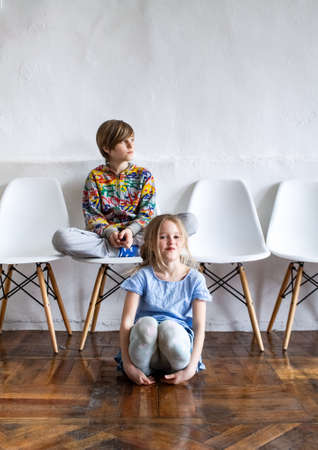 A boy and a girl play together in a spacious room with many white chairs against a white wall. Festival "On the way". 04.18.2021. 13 line, 34. Space loft "Library"のeditorial素材