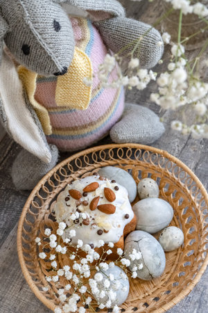 Easter. A festive Easter bunny, a toy, stands next to a basket containing decorated, festive Easter...