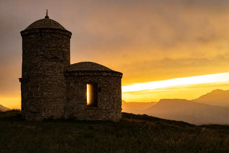 An asphalt road with a white dividing strip, in the middle of a mountain landscape and the setting sun.の写真素材