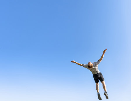 The guy is an acrobat jumping and doing somersaults against the background of a clear, cloudless,...