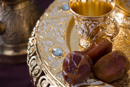 Still life with traditional golden arabic coffee set with dallah, coffee pot (jezva), cup and dates. Dark background. Horizontal photoの写真素材