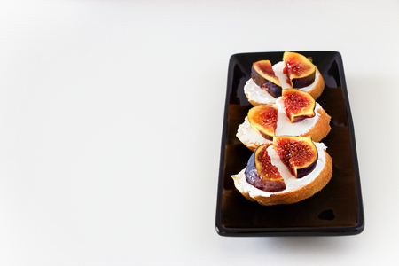 Toast Bruschetta with fresh Fig, Goat Cheese on black Plate. White background. Selective focus.の写真素材