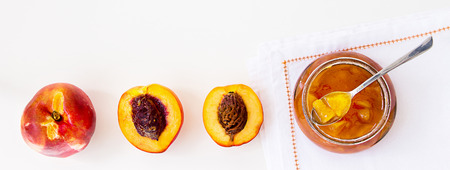 Fruits Nectarine (Peach, Apricot) jam confiture in glass jar and spoon on white background - concept healthy food banner. Copy space for your text. Top view.の写真素材