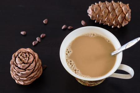 Coffee or milk tea chai with pine nuts cedar vegan milk. Black wooden background and cones of Siberian cedar pine. Top view. Selective focus.の写真素材