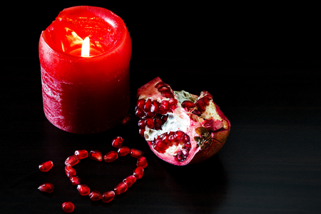 Still life with red candle and pomegranate heart. Concept romantic card.の写真素材