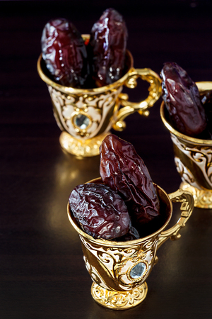 Still life with dates and goldenTraditional Arabic coffee set with mini cup. Dark background. Vertical photo.の写真素材