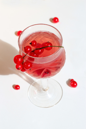 Pink champagne wine jelly with red currant in a glass, bright daylight, on white background. Top view. Copy spaceの写真素材