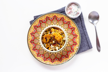 Halal Indian chicken Biryani served with yogurt tomato raita over white background. Selective focus. Top view.の写真素材