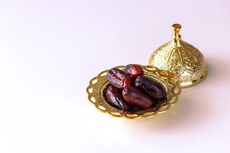 Organic dried dates in traditional arabic golden plate. Holy month Ramadan concept. Top view. Light...