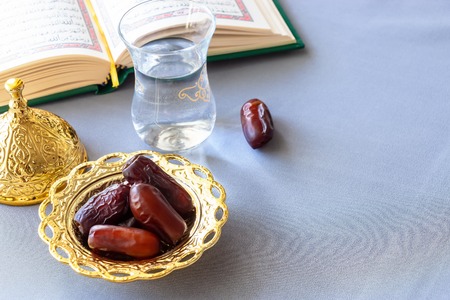 Still life Organic dates, cup of pure drinking water and quran book. Iftar Ramadan concept. Selective focus. Copy space.の写真素材