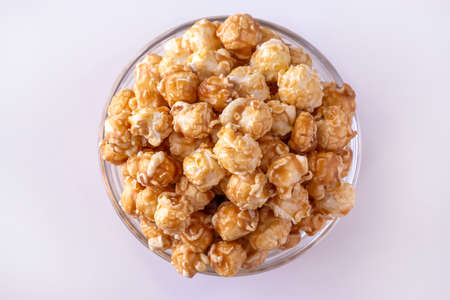 Sweet caramel popcorn in glass bowl. Close up. White background. Top view.の写真素材