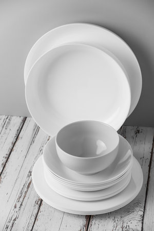 a set of white ceramic tableware on a light background. Various types of white plates, bowls and platters, cups, saucers, milkmen. Simple tableware for use at home or in a cafe.の写真素材