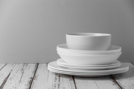 a set of white ceramic tableware on a light background. Various types of white plates, bowls and platters, cups, saucers, milkmen. Simple tableware for use at home or in a cafe.の写真素材
