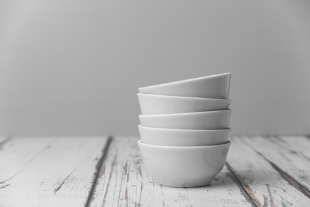 a set of white ceramic tableware on a light background. Various types of white plates, bowls and platters, cups, saucers, milkmen. Simple tableware for use at home or in a cafe.の写真素材