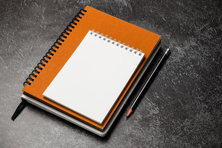 Blank notebook and pencil on black table. Mockup for designの写真素材