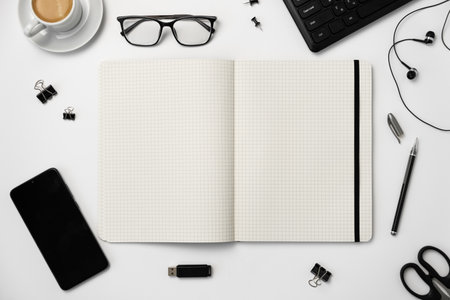 Top view of office desk table with blank notepad, smartphone, stationery and coffee cupの写真素材