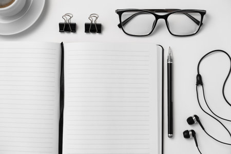 Office desk table with notepad, coffee cup, eyeglasses and headphones. top view with copy spaceの写真素材