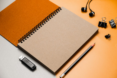 Blank brown notebook with pencil and usb drive on orange background.の写真素材