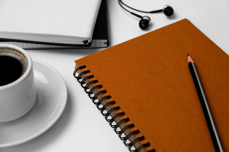 Cup of coffee with notebook and pencil on white table, stock photoの写真素材