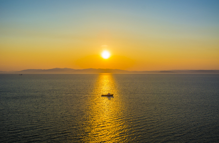 the ship sails at sunset, in the Golden reflection from the Sunの写真素材