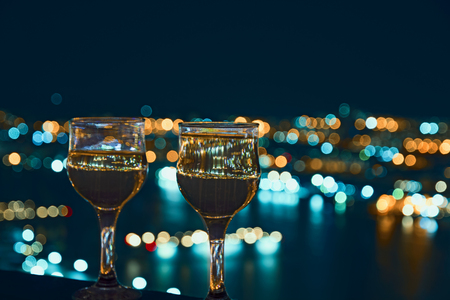 beautiful night scenery, goblets with drink stand in the background of the city at night, and the bridge with lightsの写真素材