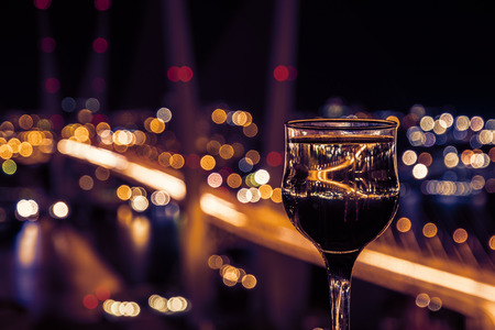 beautiful night scenery, goblets with drink stand in the background of the city at night, and the bridge with lightsの写真素材