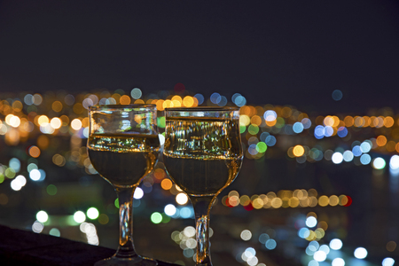 beautiful night scenery, goblets with drink stand in the background of the city at night, and the bridge with lightsの写真素材