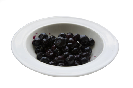 black currant on a white plate, on an isolated white background.の写真素材