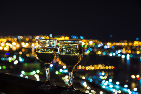 beautiful night scenery, goblets with drink stand in the background of the city at night, and the bridge with lightsの写真素材