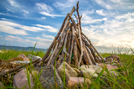 bonfire of wood on the beach near the sea. around the decorated stones. under the blue skyの写真素材